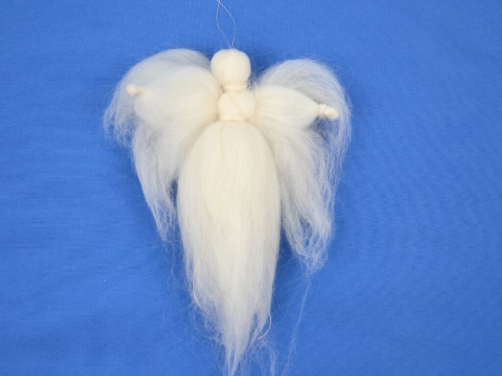 A white wool angel finished with a golden thread.
Blue background,