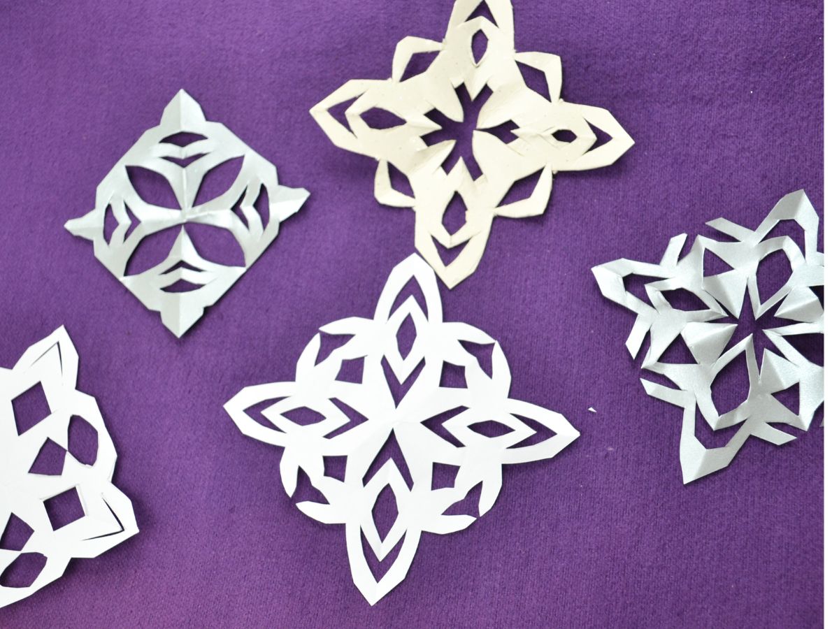5 paper snowflakes on a purple top