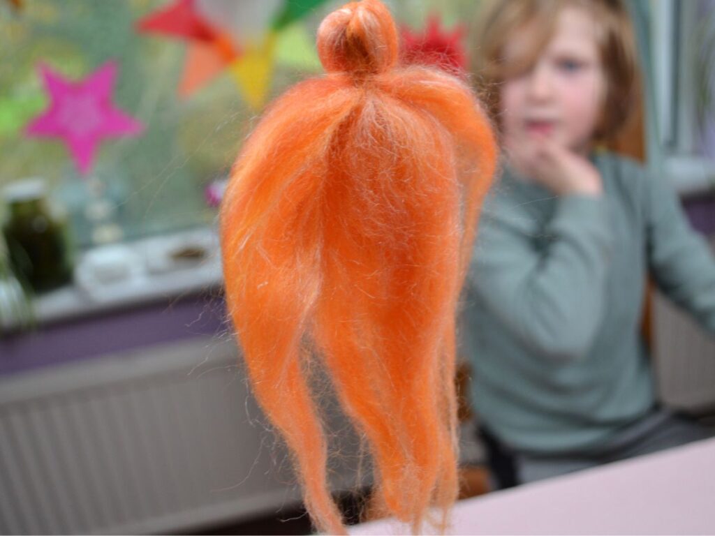 A felt orange angel with a boy besides a window on the background