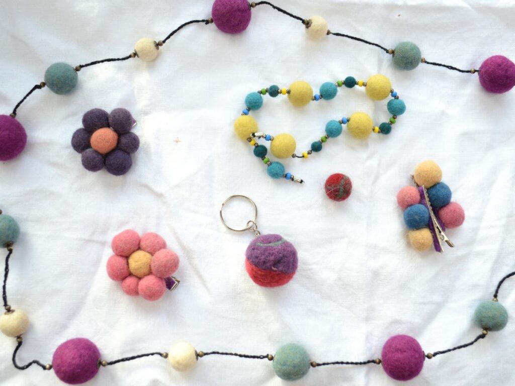 Felt necklace, bracelet hair clip and keychain on a white surface