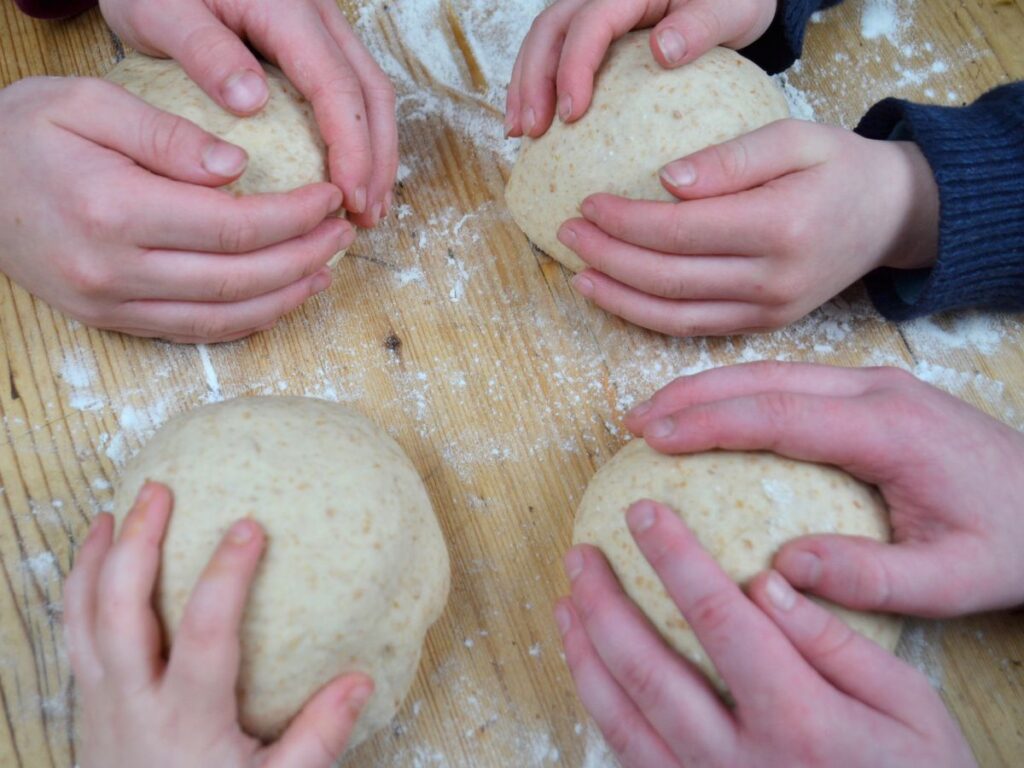 four balls of bread dough each hold by a childs hand