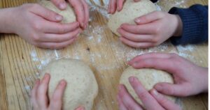 four balls of bread dough each hold by a childs hand