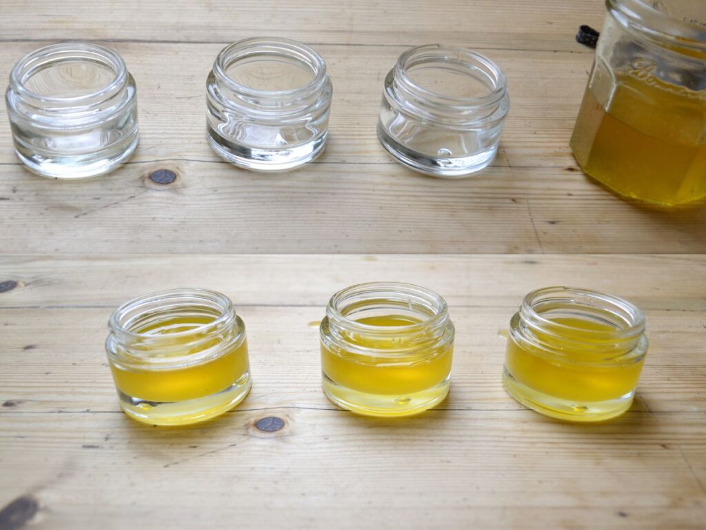 Three clean empty cosmetic jars,a jar with oil and three cosmetic jars with calendula salve
