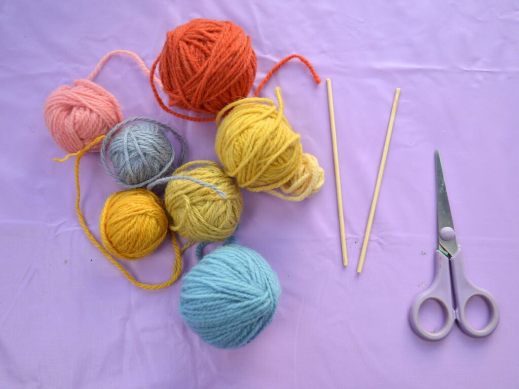 colour yarn scissors and two sticks.