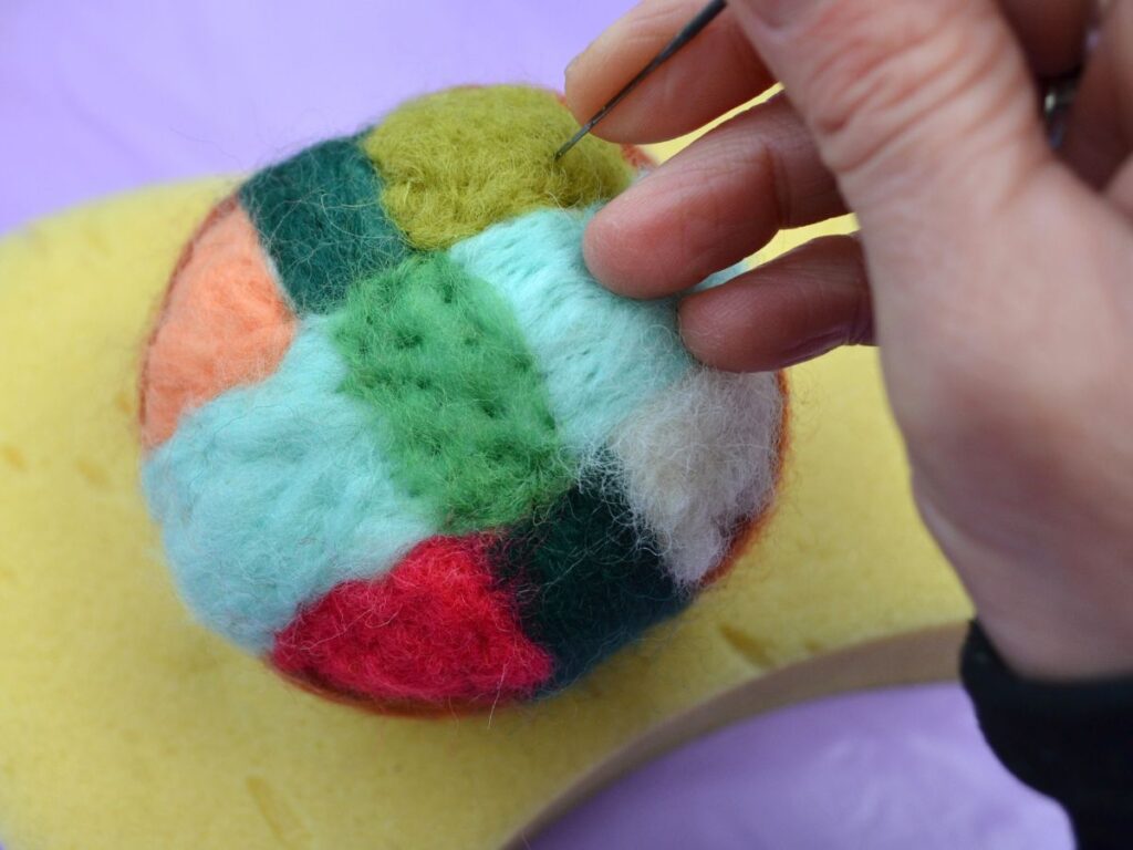 A coloured needle felt ball is used by hand with a felt needle.
