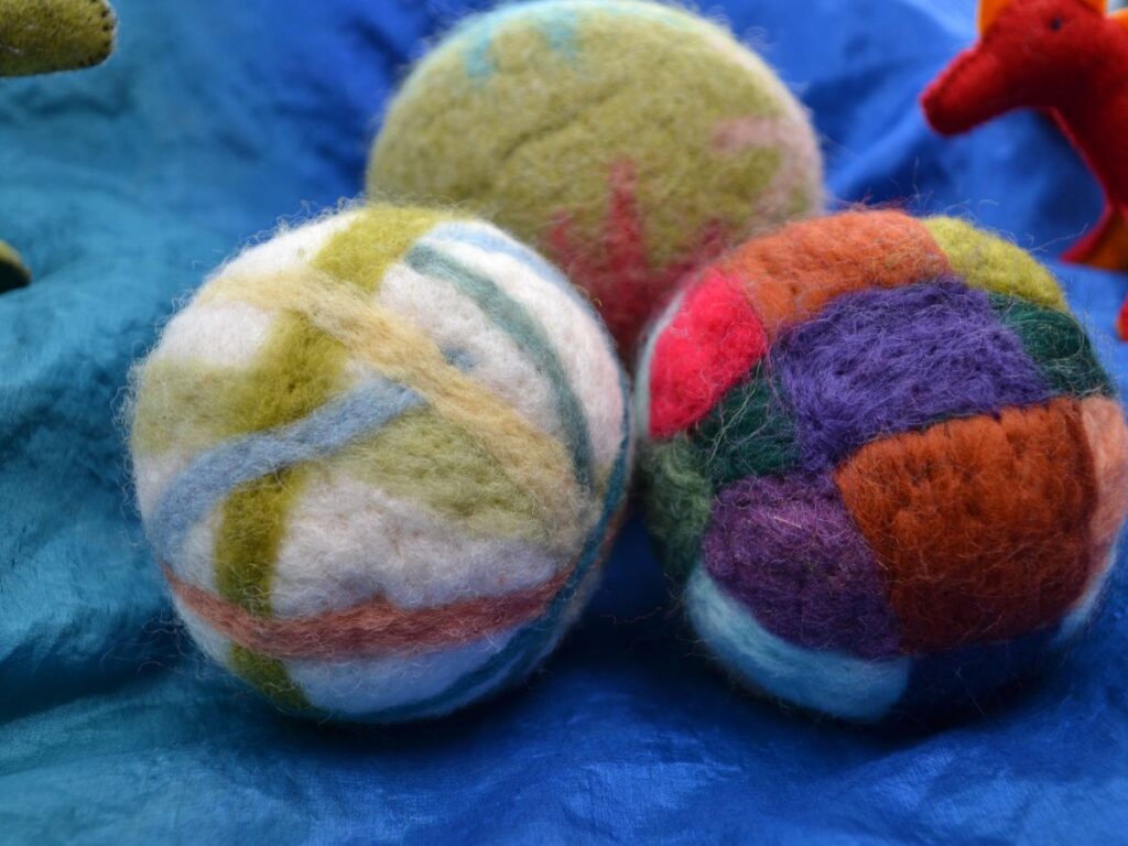 Three needle-felt balls on a blue silk.