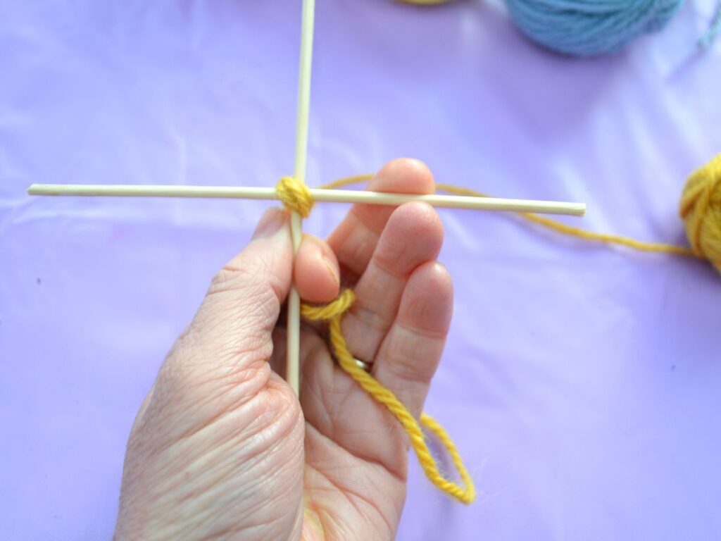 a cross made with sticks with yarn in the middle, the first step of a God's eye.