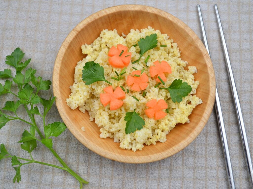 a wooden bowl with millet, carrot flowers, and parsley.