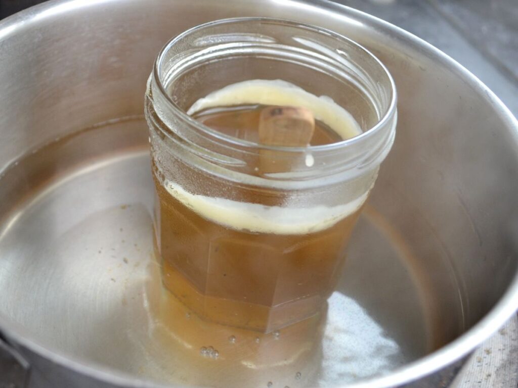 A jar with melting beeswax in a pan with simmering water.