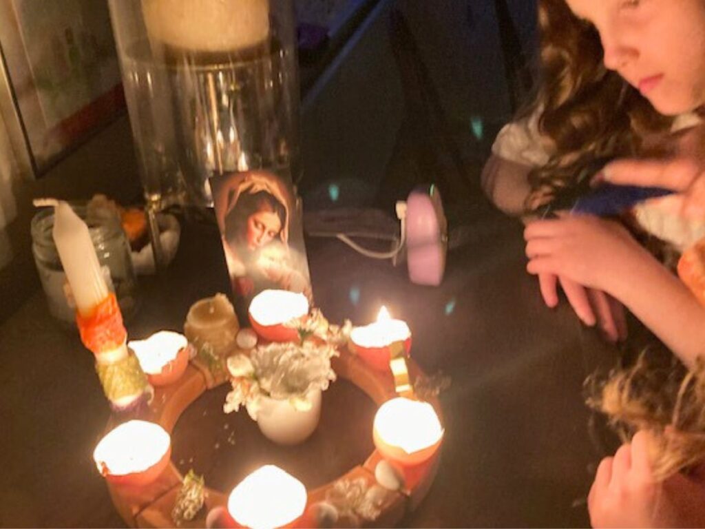 a girl looking at a wooden ring with flowers and eggshell candles.