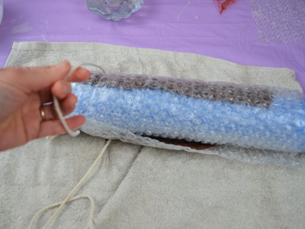 Untying the pool noodle and bubble wrap.