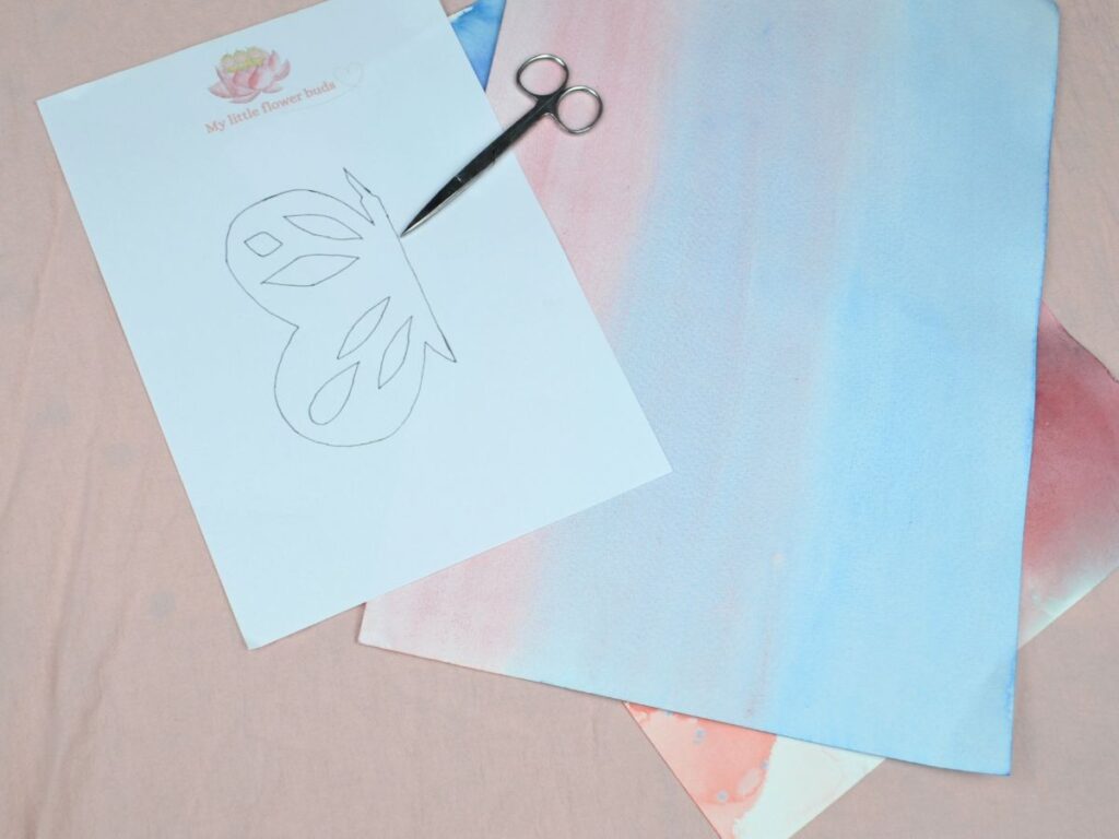 A butterfly template, scissors and a watercolour painting.