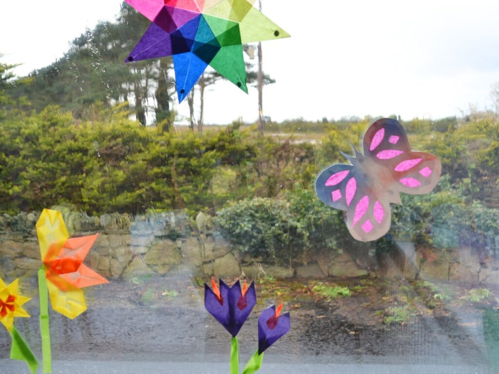 Paper butterfly, paper flowers and paper star glue to a window.
