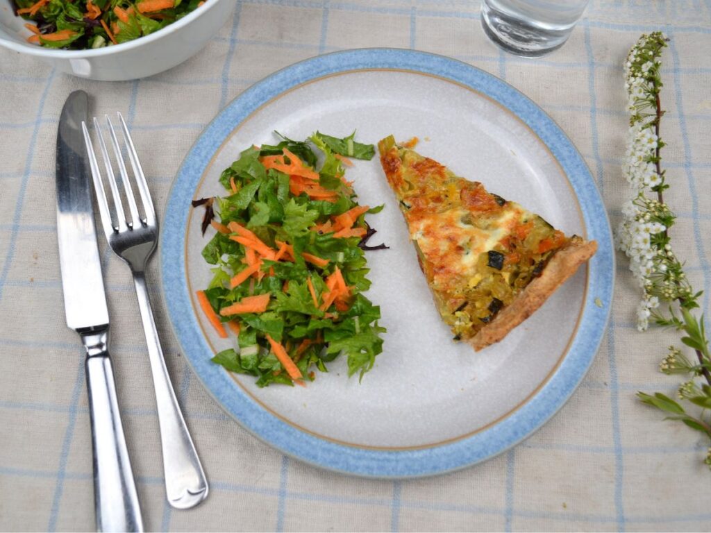 a plate with green salad ans a slice of spelt vegetable tart