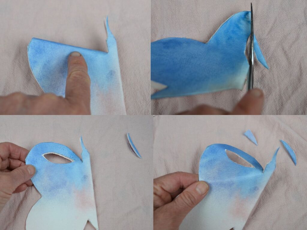 A hand cutting a paper butterfly wing design.
