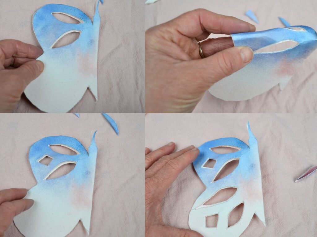 A hand cutting a paper butterfly wing design.