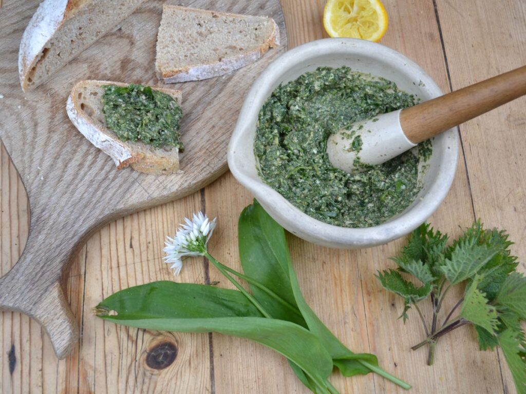 Wild garlic and Nettles pesto in a mortar and pestle and on a piece of bread.