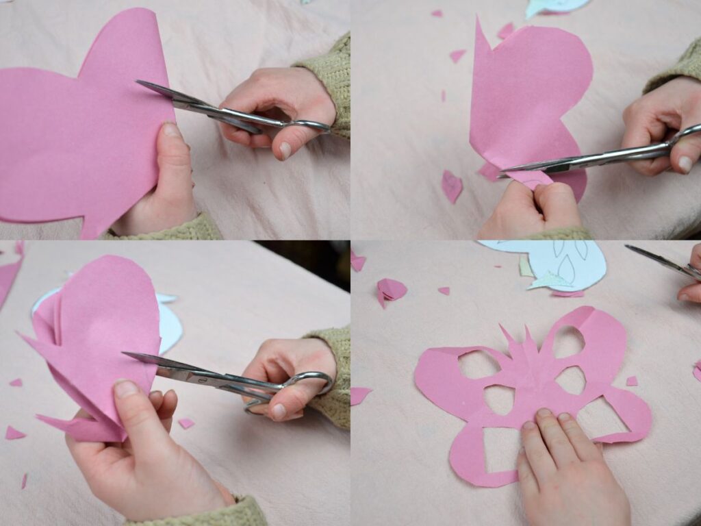 A childs hand cutting a paper butterfly.
