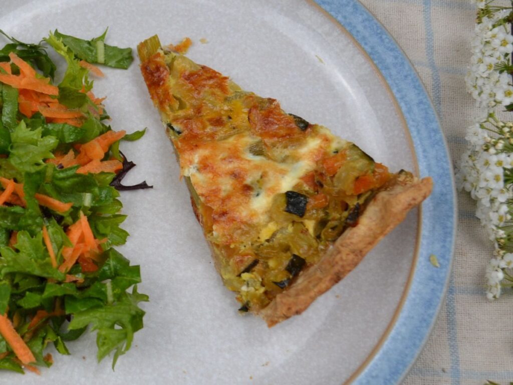 a plate with green salad ans a slice of spelt vegetable tart