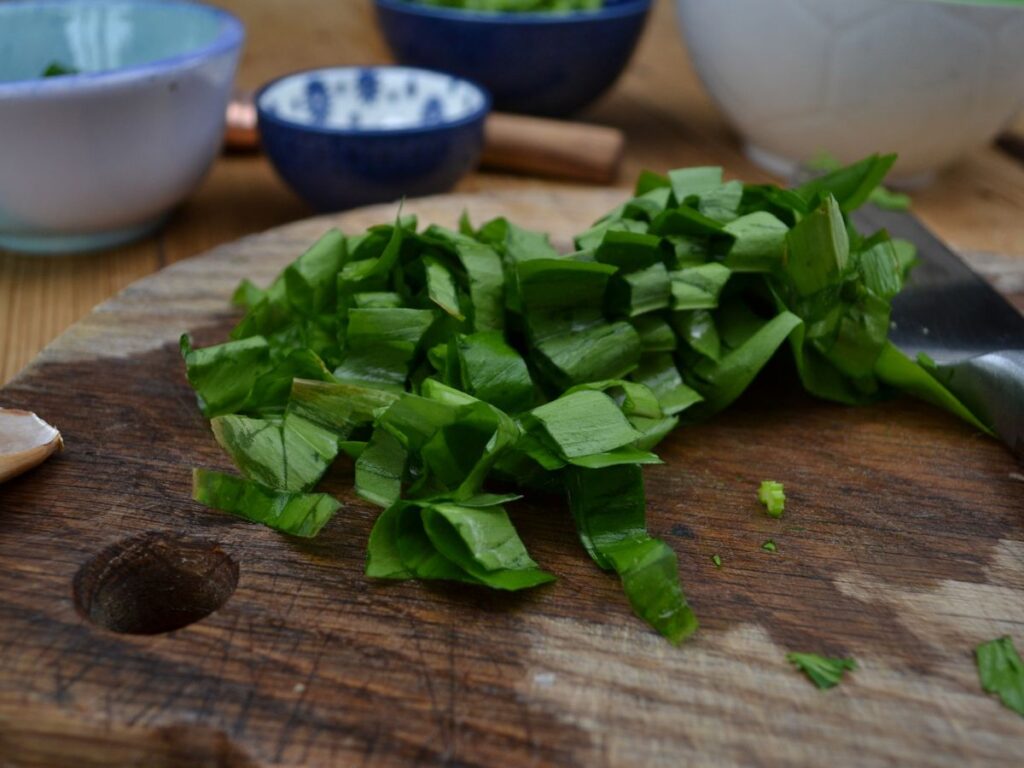 A wooden chopping board with wild garlic.