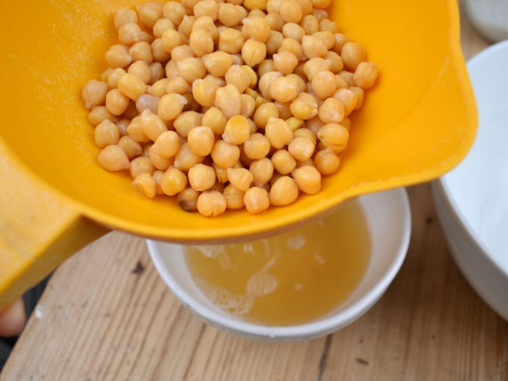 Chickpeas on a sieve over a bowl.
