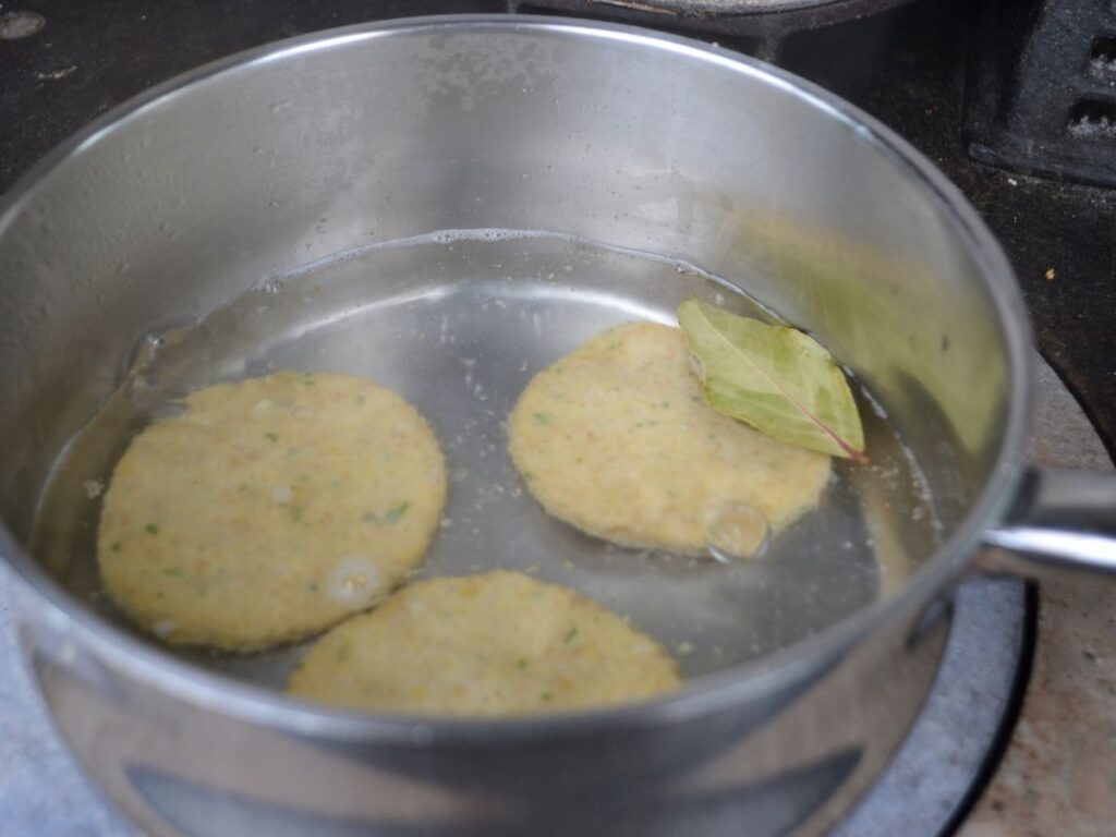 3 Chickpea Schnitzels are boiled in a saucepan.