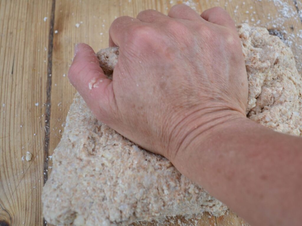 A hand kneading a rice bread dough.
