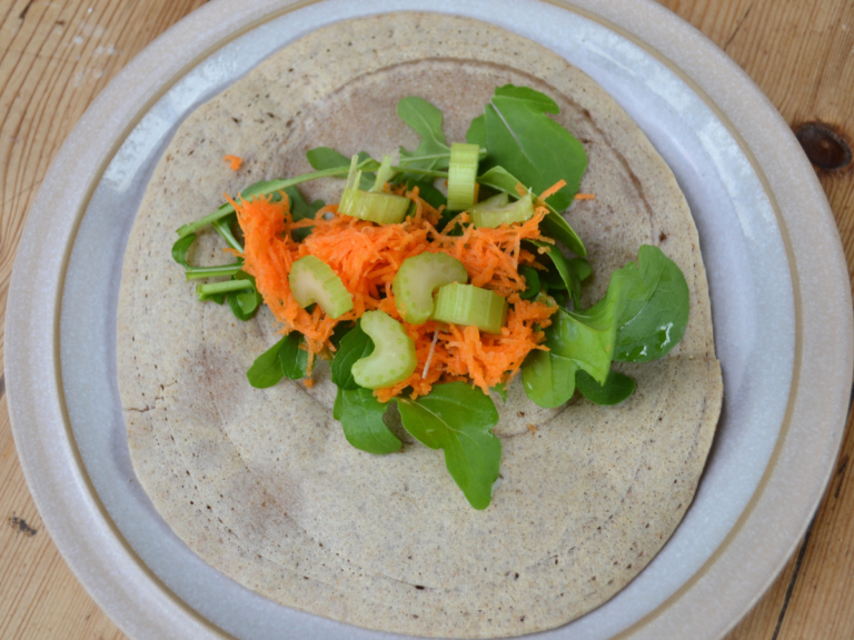 A buckwheat crêpe on a plate with a salad on top.
