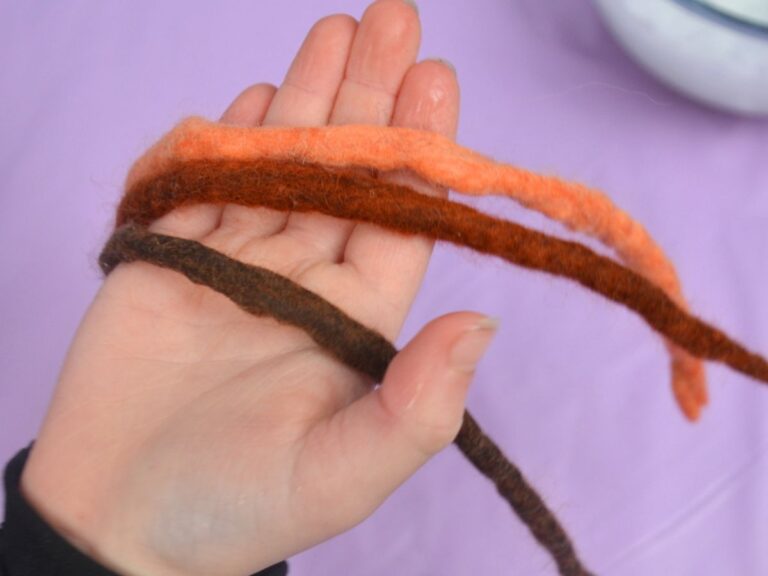 Three wet-felted strands on a child's hand.