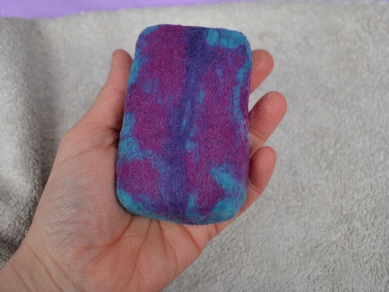 A hand holding a wet felted soap.