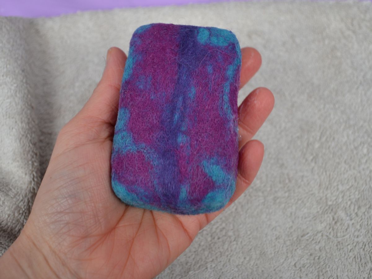 A hand holding a wet felted soap.