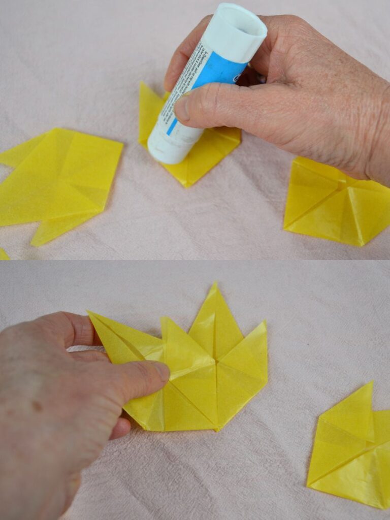 A hand glues Autumn paper leaves together.