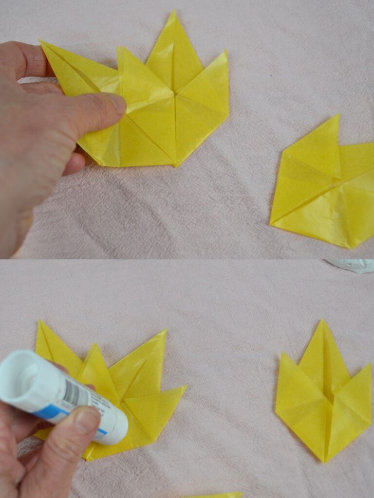 A hand glues Autumn paper leaves together.