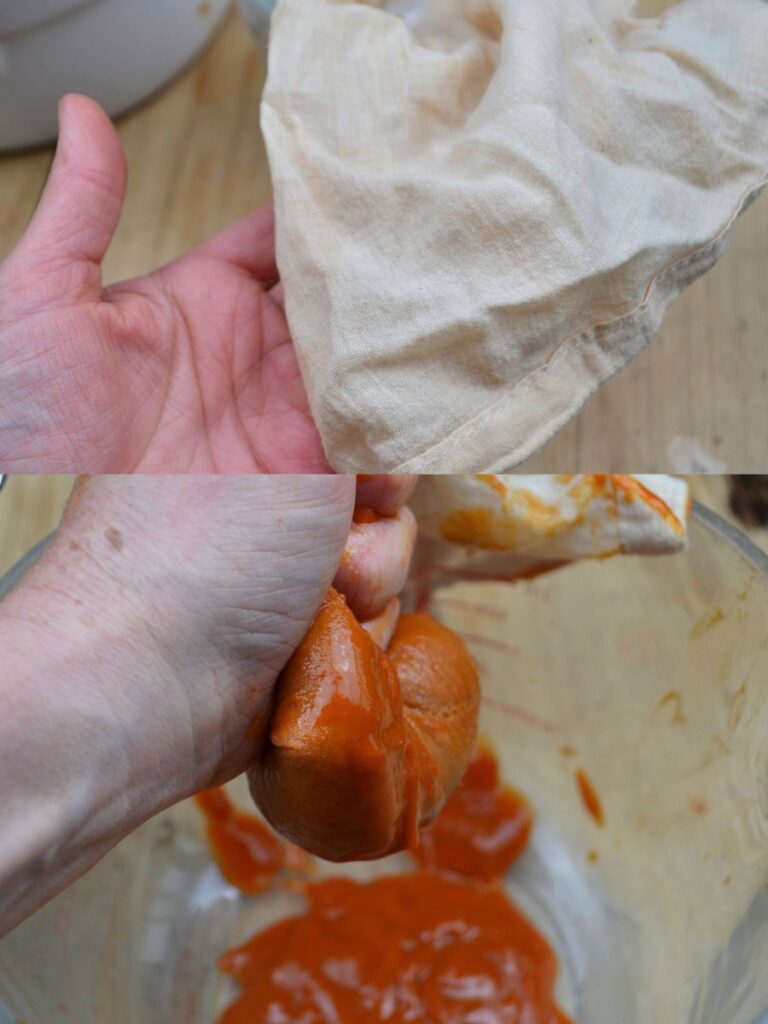 A hand holding a cheesecloth and a hand pressing rosehip puree through a cheese bag.