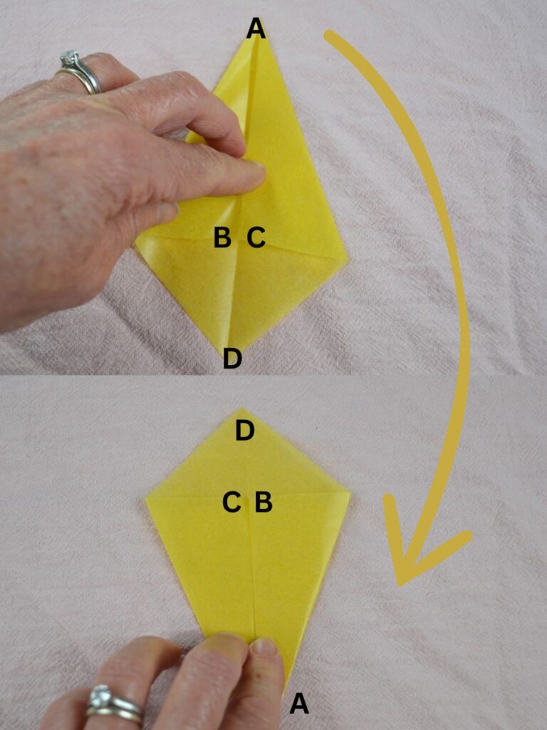 A hand holding a kite-shaped piece of kite paper