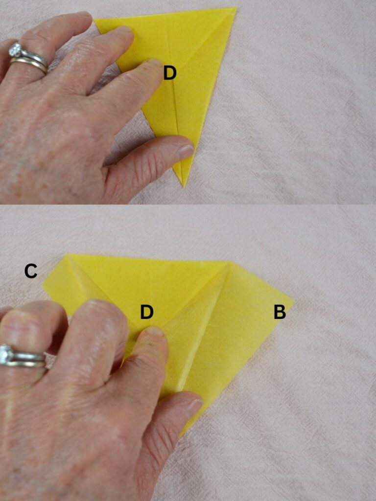 A hand folding the top point of a kite-shaped piece of kite paper.